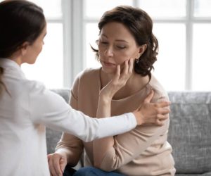 Loving young adult daughter touch caress support unhappy sad old Caucasian mother feeling distressed depressed at home. Supportive grownup girl comfort upset middle-aged mom mourning yearning.